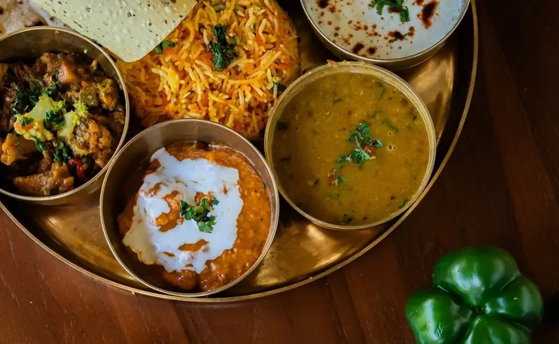 Close-up of dal, paneer curry and vegetable rice in a brass thali at Bali Yoga Retreats