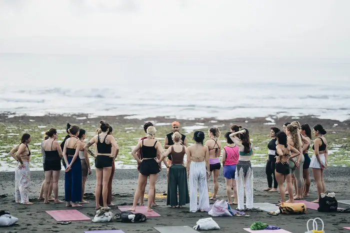 A full group of retreat guests practising together on a Bali beach