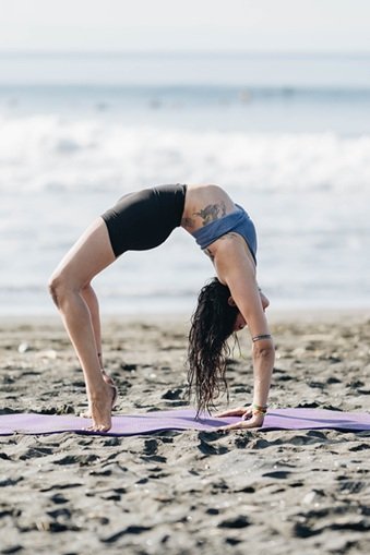 Woman Practising Bridge Pose at Beach